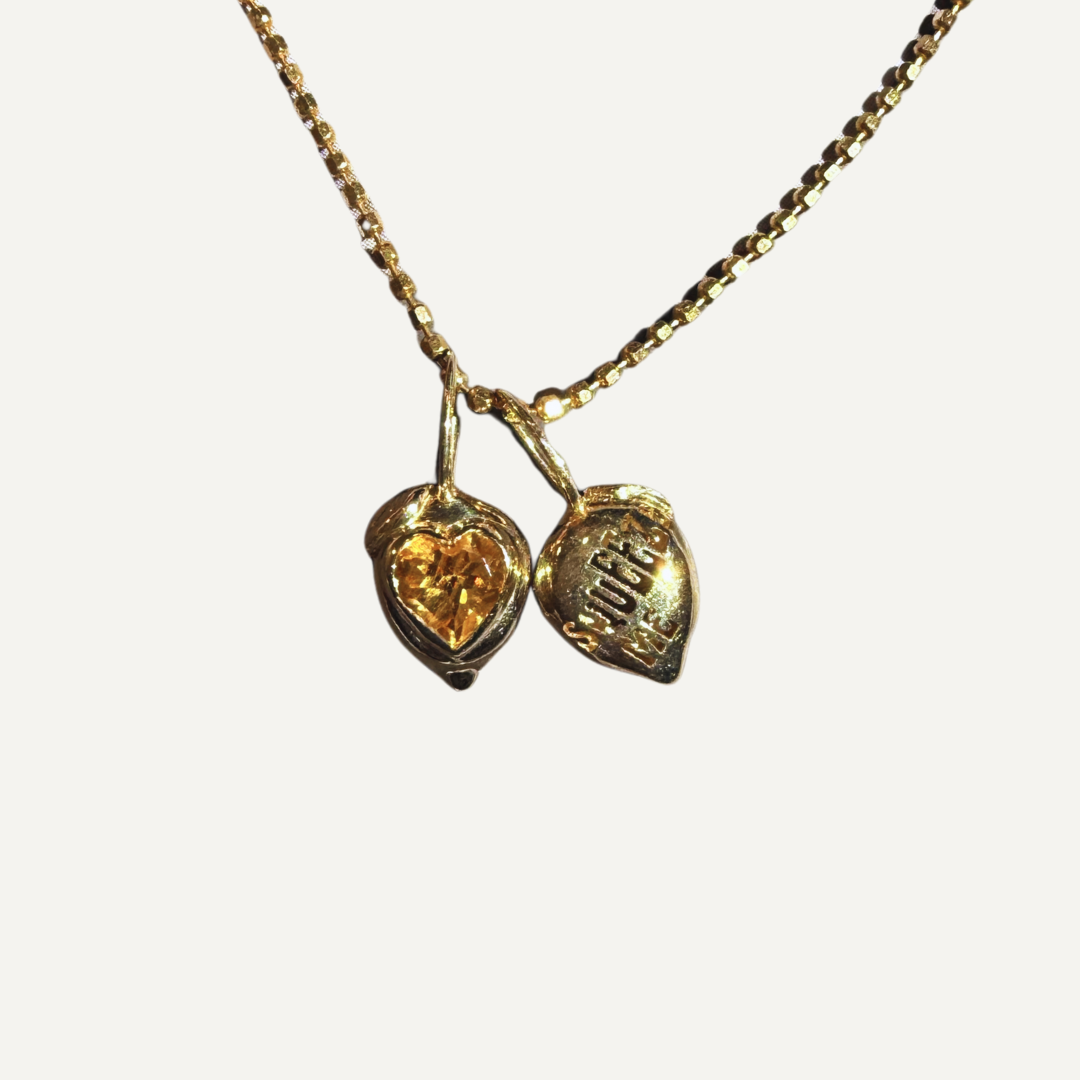 Gold necklace lemon shaped pendants with heart shaped citrine on a white background