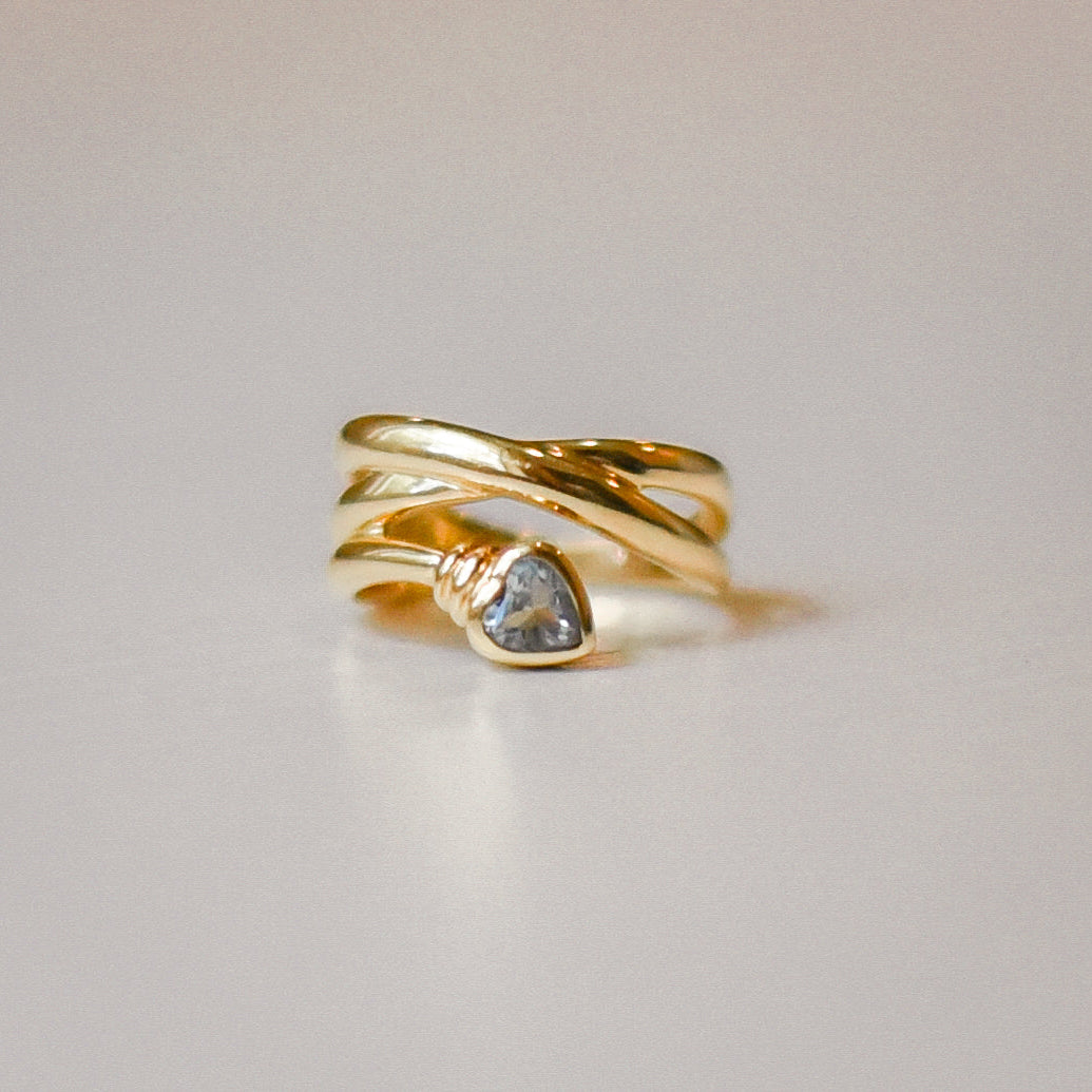 Gold ring with an aquamarine gemstone on a light gray background