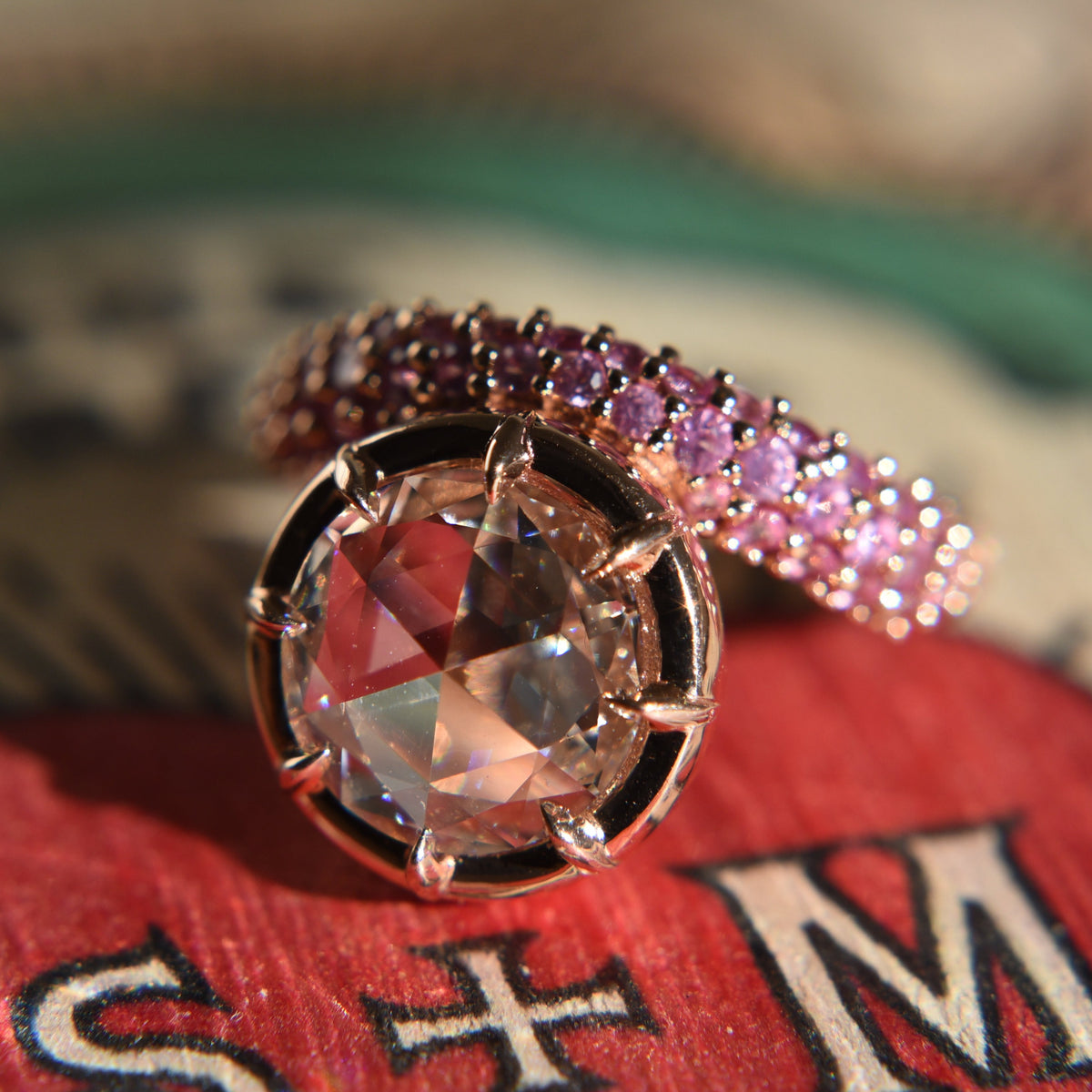 Close-up of a rose cut diamond ring with claw prong setting on an asymmetrical wavy pink sapphire gold band.