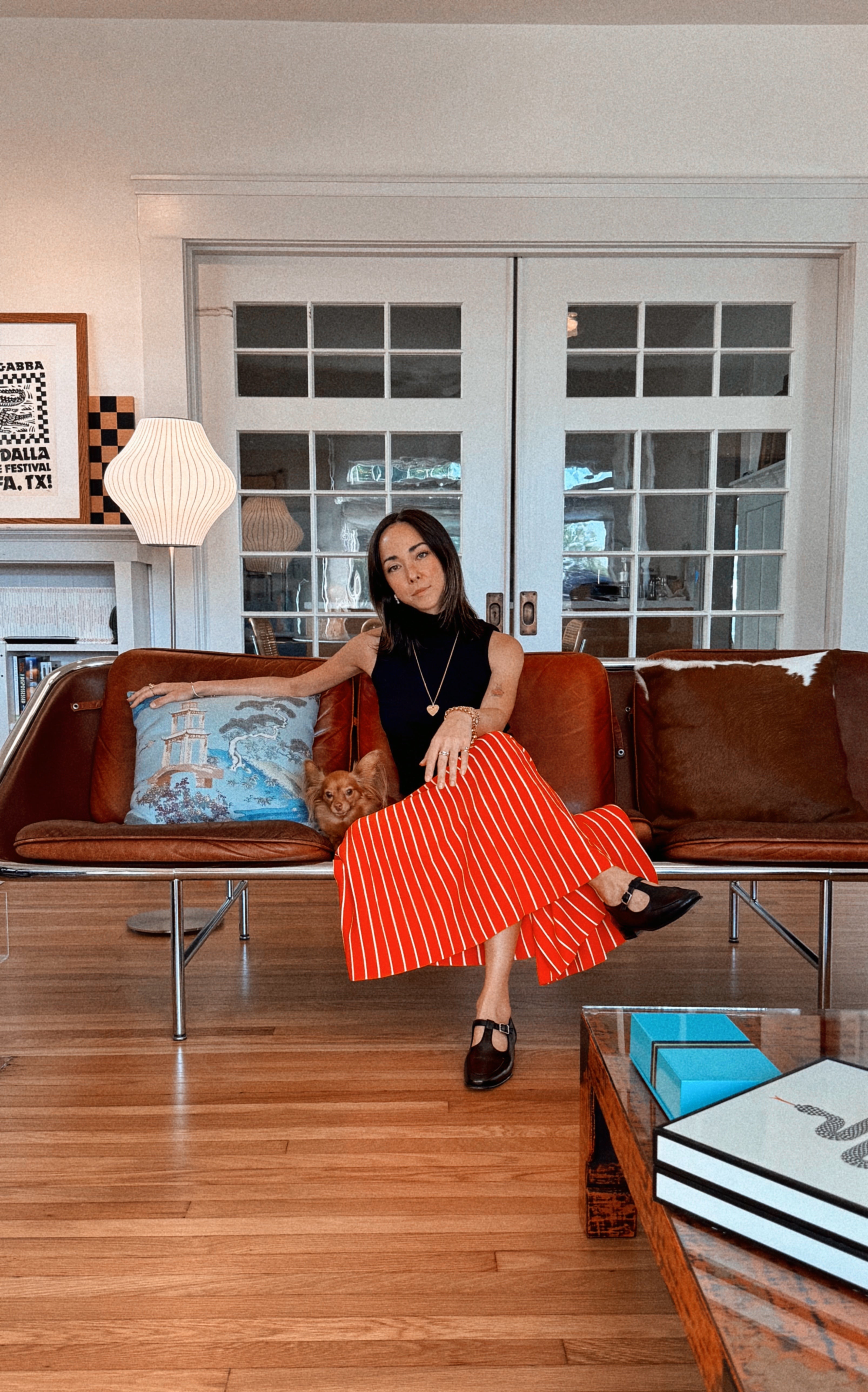 Woman in a red dress sitting on a brown leather sofa in a living room.