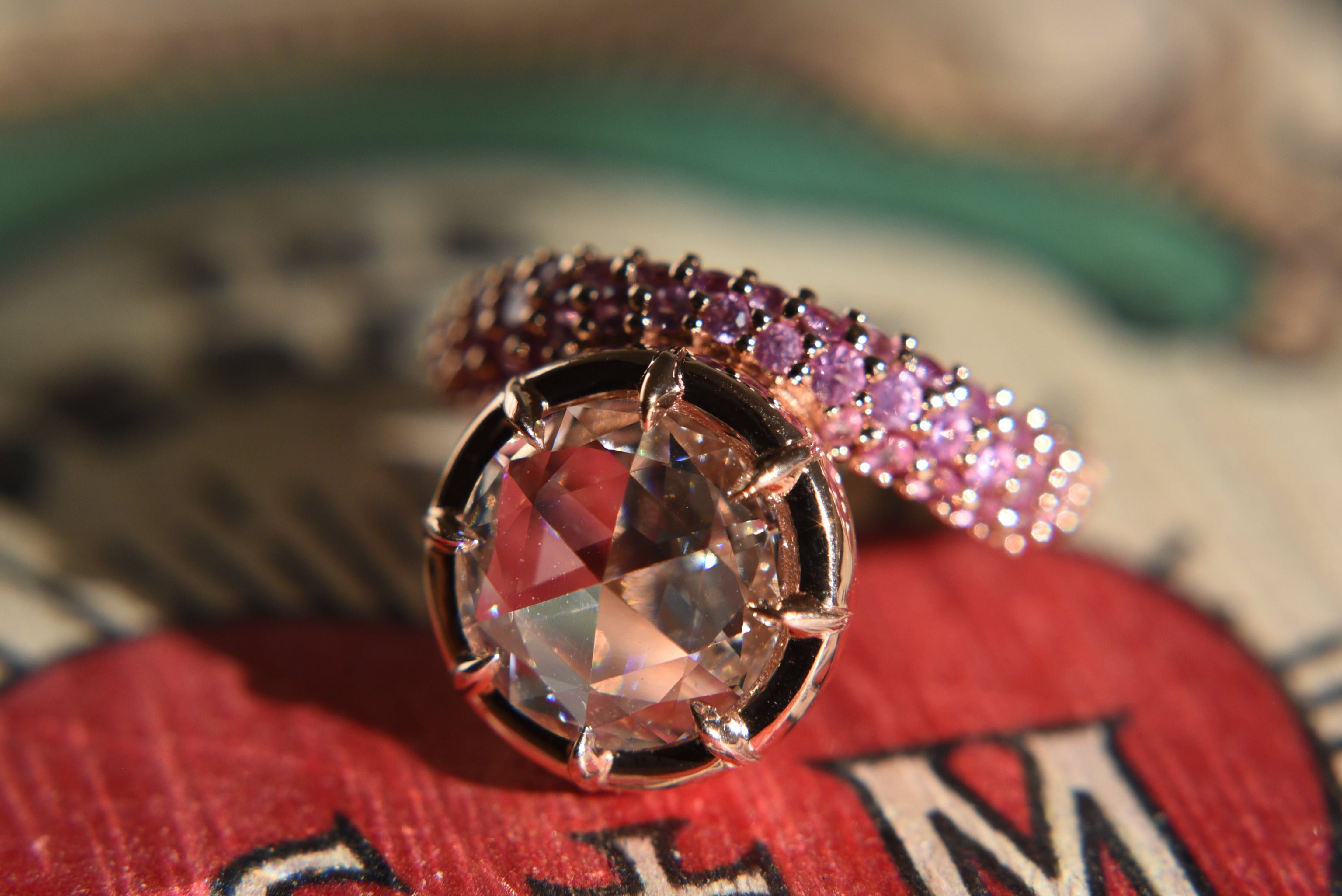 Close-up of a rose cut diamond ring with claw prong setting on an asymmetrical wavy pink sapphire gold band.