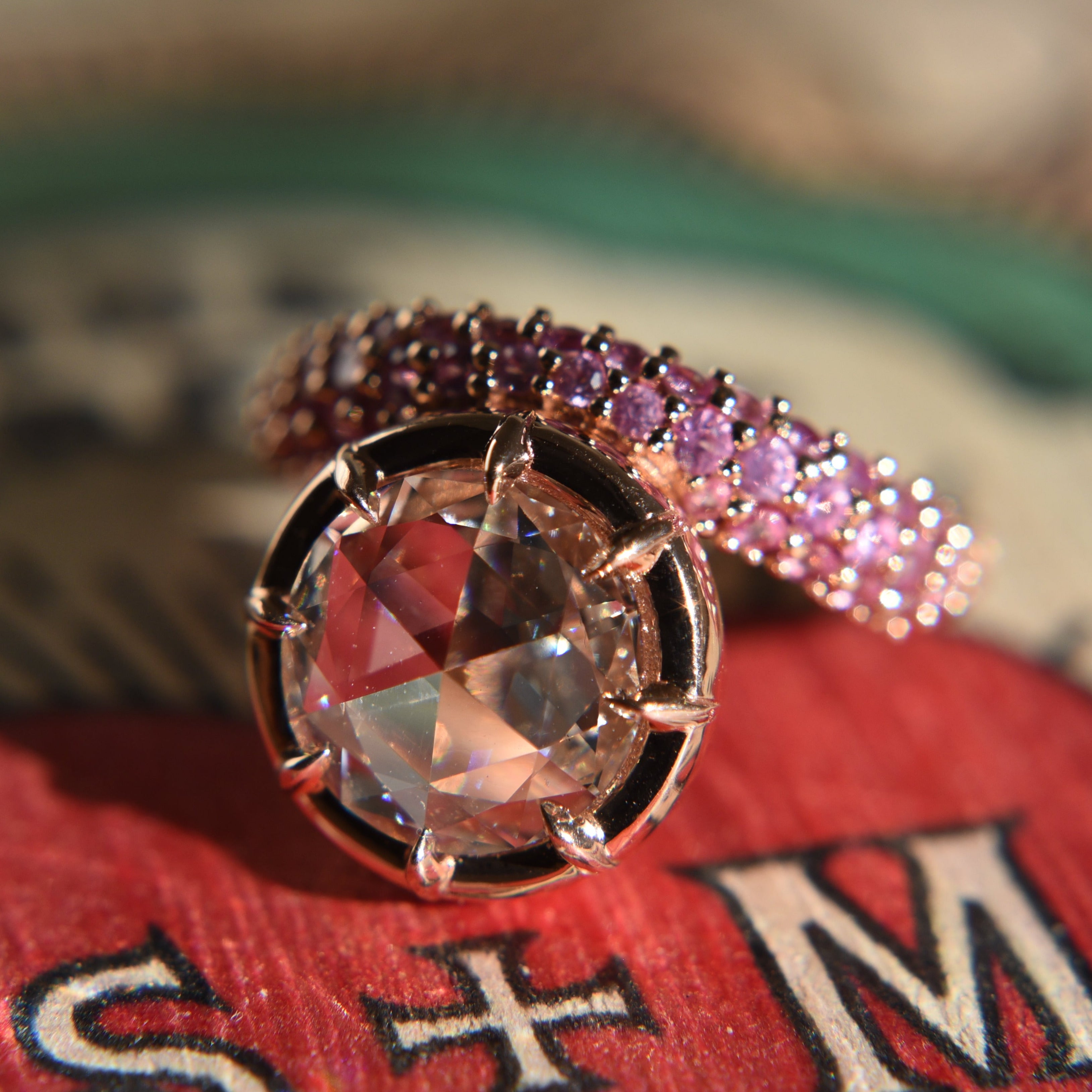 Close-up of a rose cut diamond ring with claw prong setting on an asymmetrical wavy pink sapphire gold band.