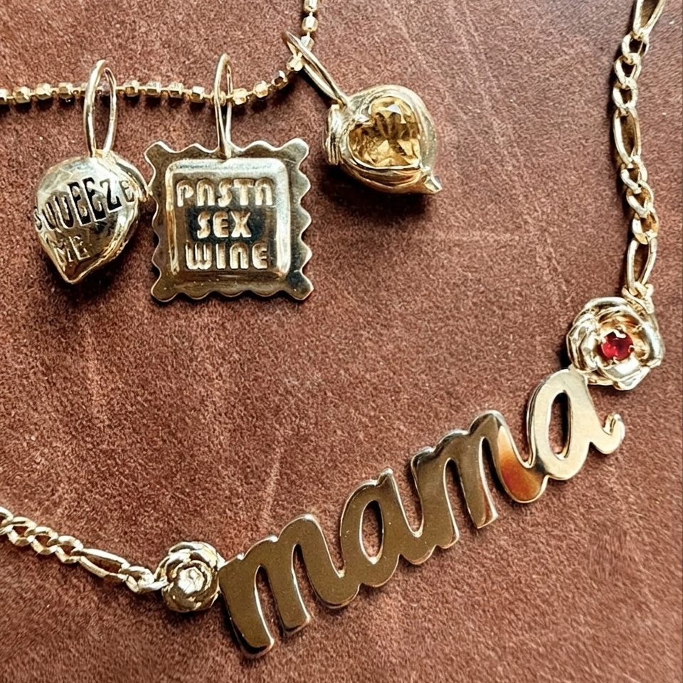 Necklace with 'mama' charm and three charms on a brown background
